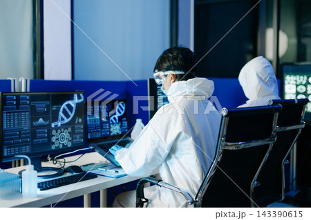 Scientist in protective hazmat suit analyzes DNA data and scientific charts on a modern computer screen in a medical laboratory Scientist in protective hazmat suit analyzes DNA data and scientific charts on a modern computer screen in a medical laboratory 143390615