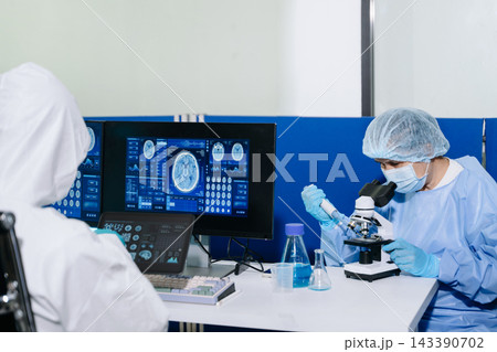 Medical researchers in PPE collaborate to analyze digital brain scans and biotechnology data on monitors and tablets Medical researchers in PPE collaborate to analyze digital brain scans and biotechnology data on monitors and tablets 143390702