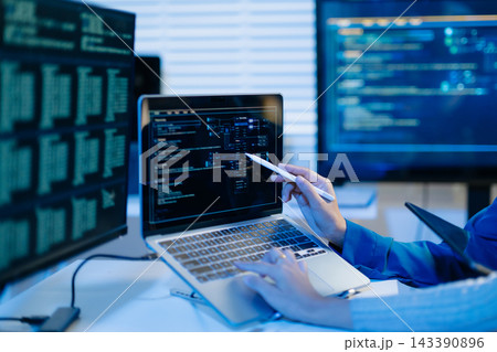 Two female programmers collaborate late in a modern tech office, analyzing computer code on screens to optimize software development Two female programmers collaborate late in a modern tech office, analyzing computer code on screens to optimize software development 143390896