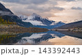 Serene mountain lake reflection showcases peaceful autumn landscape and snow peak wilderness in canada under majestic cloudy sky 143392443
