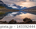 Serene mountain lake reflection reveals peaceful nature under golden sunset in Canada with snowy peak mirroring calm water 143392444