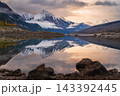 Serene alpine mountain reflection glows across calm lake water in Canada wilderness under dramatic peaceful sunset sky view 143392445