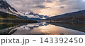 Serene canada mountain lake landscape displaying majestic snowy peak reflection during peaceful sunset under dramatic tranquil sky 143392450
