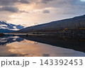 Serene lake reflection captures dramatic sunset sky above mountain wilderness in scenic canada providing deep tranquil harmony 143392453