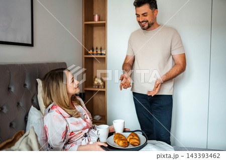 Man serving woman breakfast in bed on a romantic morning Man serving woman breakfast in bed on a romantic morning 143393462