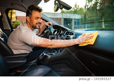 Man cleaning car dashboard with microfiber cloth 143393527