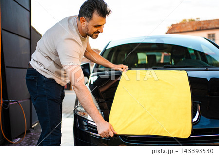 Man drying car with microfibre cloth after washing Man drying car with microfibre cloth after washing 143393530