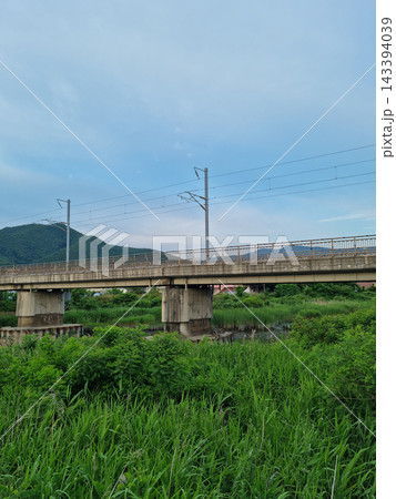 It is a rural landscape with a bridge over which a train passes. 143394039
