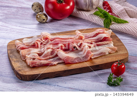 Wooden cutting board with raw sliced bacon, red tomato and quail eggs breakfast meat Wooden cutting board with raw sliced bacon, red tomato and quail eggs breakfast meat 143394649