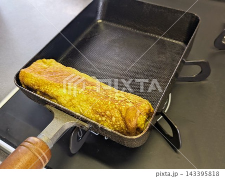 四角い鉄フライパンで丁寧に巻き上げられた和食の定番玉子焼き 143395818