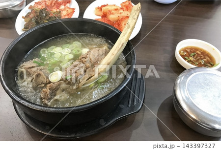 骨付き肉が入った熱々のスープとキムチが並ぶ韓国料理の食卓 骨付き肉が入った熱々のスープとキムチが並ぶ韓国料理の食卓 143397327