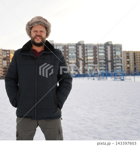 Front view of an angry aggressive bearded man growling on snow outdoors wearing warm winter fur hat. Front view of an angry aggressive bearded man growling on snow outdoors wearing warm winter fur hat. 143397603