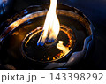 Close-up of a traditional oil lamp with a glowing flame in low light, symbolizing peace, spirituality, meditation, and hope 143398292