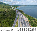Drone aerial view of a highway running beside a reservoir with lush green mountains, Transportation infrastructure and renewable energy concept 143398299