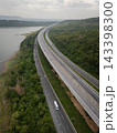 Drone aerial view of an elevated highway crossing lush forest and mountain landscape under dramatic clouds, The modern transportation infrastructure and nature concept 143398300
