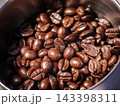 Close-up of freshly roasted coffee beans inside a coffee grinder hopper. Rich texture and aroma for espresso concept 143398311
