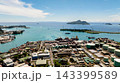 Harbor with industrial buildings, storage tanks, containers, and turquoise sea, with green islands in the background. Seychelles, Mahe. Victoria. 143399589