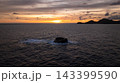 Distant islands form dark silhouettes against a sunset sky filled with warm hues. Seychelles, Mahe. 143399590