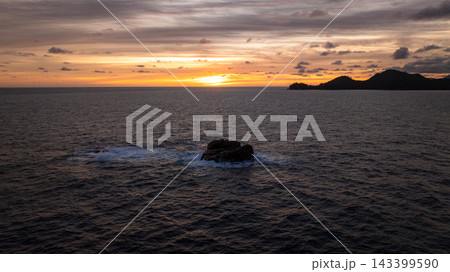 Distant islands form dark silhouettes against a sunset sky filled with warm hues. Seychelles, Mahe. 143399590