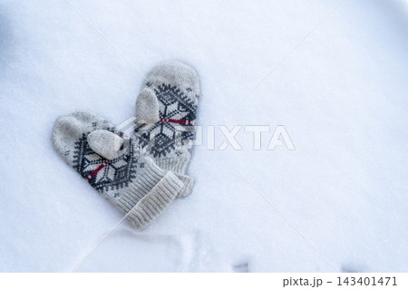 Knitted Winter Mittens with Ornament Pattern Lying on White Snow Top View 143401471