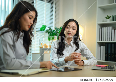 Two Asian Businesswomen Collaborating Over Tablet in Modern Office Workspace Two Asian Businesswomen Collaborating Over Tablet in Modern Office Workspace 143402909