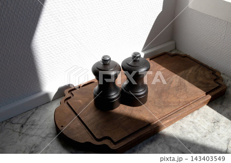 Salt and pepper grinders on wooden board. 143403549