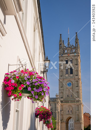 The tower of St Mary's Church, a large historic church located in central Warwick, UK. A hanging basket of flowers in the foreground. The tower of St Mary's Church, a large historic church located in central Warwick, UK. A hanging basket of flowers in the foreground. 143403928