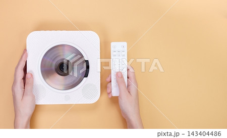 Modern White CD Player with Remote Control on a Yellow Background, Minimalist Style. 143404486