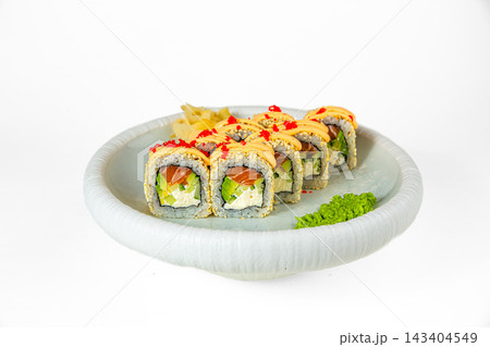 Sushi roll in sesame with salmon, cream cheese and avocado topped with spicy sauce and red tobiko on white plate, isolated on white background Sushi roll in sesame with salmon, cream cheese and avocado topped with spicy sauce and red tobiko on white plate, isolated on white background 143404549