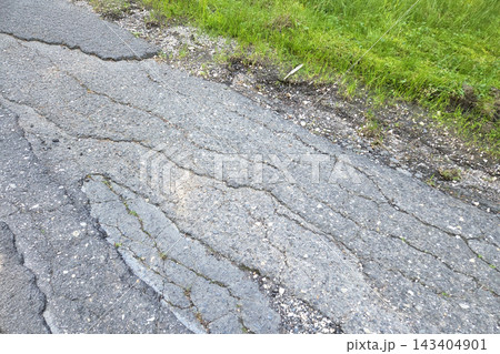 Cracked Asphalt Road with Green Grass Edge Urban Decay and Infrastructure Concept for Design Cracked Asphalt Road with Green Grass Edge Urban Decay and Infrastructure Concept for Design 143404901