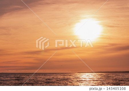 A golden sunset spills warm orange light across a calm ocean A golden sunset spills warm orange light across a calm ocean 143405108