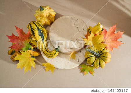 Autumn pumpkins and maple leaves on travertine podium Autumn pumpkins and maple leaves on travertine podium 143405157