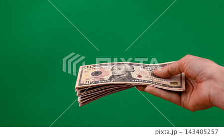 Hand holding a stack of US ten dollar bills isolated on green background with copy space Hand holding a stack of US ten dollar bills isolated on green background with copy space 143405257