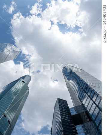 Modern glass skyscrapers with reflective facades rising against a clear blue sky in an urban setting Modern glass skyscrapers with reflective facades rising against a clear blue sky in an urban setting 143405433