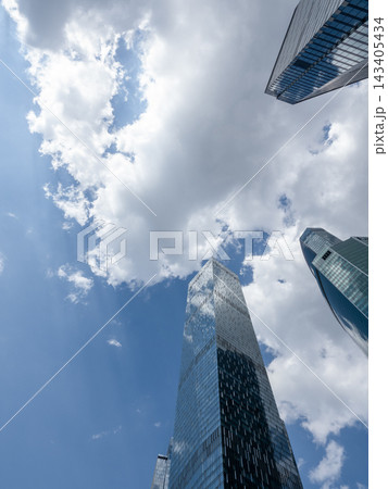 Modern glass skyscrapers with reflective facades rising against a clear blue sky in an urban setting Modern glass skyscrapers with reflective facades rising against a clear blue sky in an urban setting 143405434