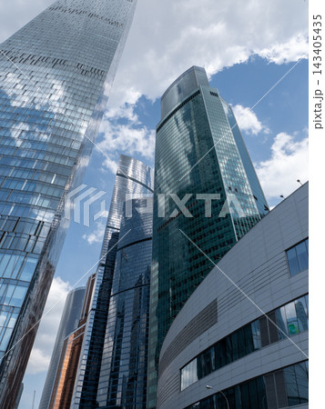 Modern glass skyscrapers with reflective facades rising against a clear blue sky in an urban setting Modern glass skyscrapers with reflective facades rising against a clear blue sky in an urban setting 143405435