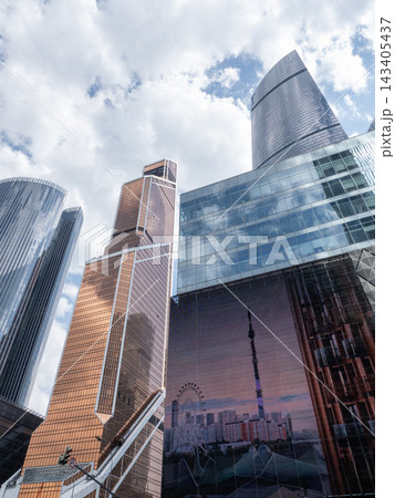 Modern glass skyscrapers with reflective facades rising against a clear blue sky in an urban setting Modern glass skyscrapers with reflective facades rising against a clear blue sky in an urban setting 143405437