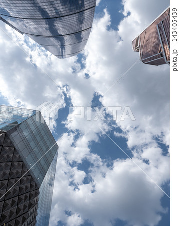 Modern glass skyscrapers with reflective facades rising against a clear blue sky in an urban setting 143405439