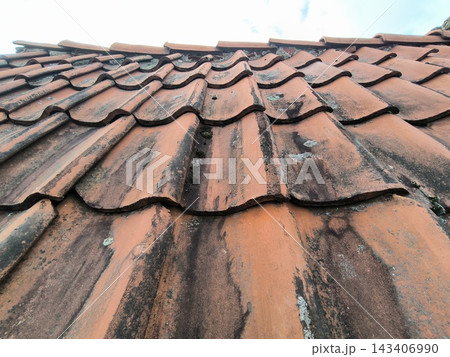 Fragment of an old tiled roof beneath the clouds 143406990