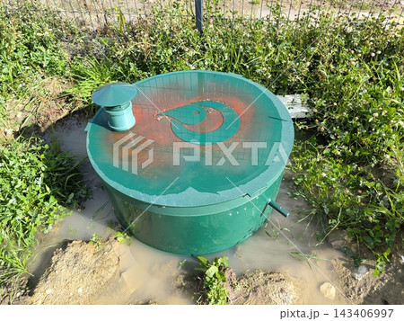 Round septic tank with ventilation amidst weeds Round septic tank with ventilation amidst weeds 143406997