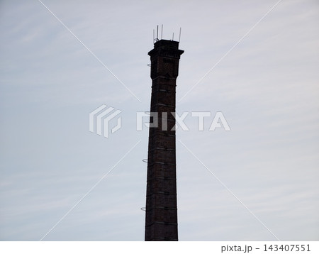 Weathered brick chimney over city. Aged brick factory chimney stands tall amidst overcast sky Weathered brick chimney over city. Aged brick factory chimney stands tall amidst overcast sky 143407551