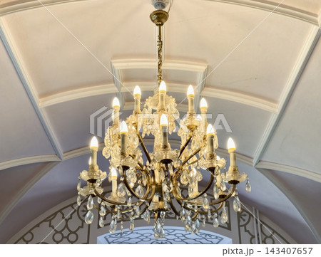 Refined crystal chandelier with warm glow elevates sophisticated mansion or hotel entrance Refined crystal chandelier with warm glow elevates sophisticated mansion or hotel entrance 143407657