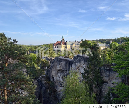 Imposing fortress amid rugged terrain. Historic castle set against towering rocks and shadowy valleys 143407823