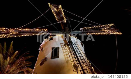 A illuminated windmill at night with decorative lights adds charm to the evening A illuminated windmill at night with decorative lights adds charm to the evening 143408126