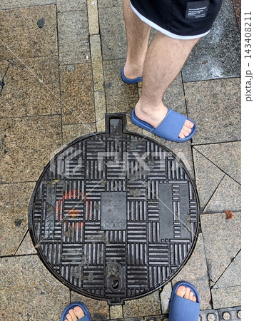 Man wearing sandals standing on wet sidewalk 143408211