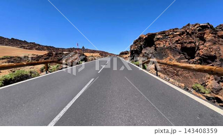 This is a scenic road located in a desert that features rocky terrain beneath a clear blue sky This is a scenic road located in a desert that features rocky terrain beneath a clear blue sky 143408359