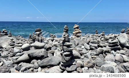 A Serene Beach featuring Beautifully Stacked Stones Set Against a Clear Blue Ocean A Serene Beach featuring Beautifully Stacked Stones Set Against a Clear Blue Ocean 143408500