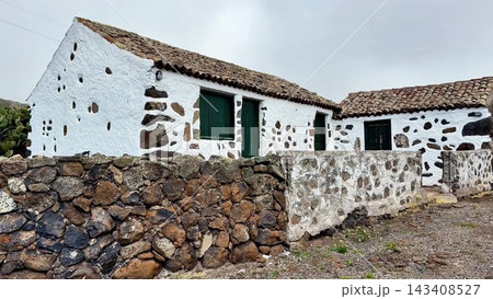 Charming Whitewashed Cottage Featuring a Stone Wall Set in a Rustic and Beautiful Landscape 143408527