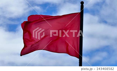 A Waving Red Flag Beautifully Contrasts Against a Bright Blue Sky Above Us Today as We Look Up A Waving Red Flag Beautifully Contrasts Against a Bright Blue Sky Above Us Today as We Look Up 143408582