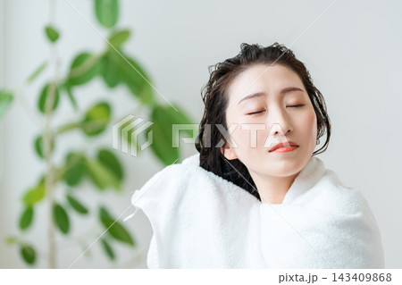 濡れた髪をタオルドライする女性。入浴後のヘアケアとリラックスタイム 濡れた髪をタオルドライする女性。入浴後のヘアケアとリラックスタイム 143409868